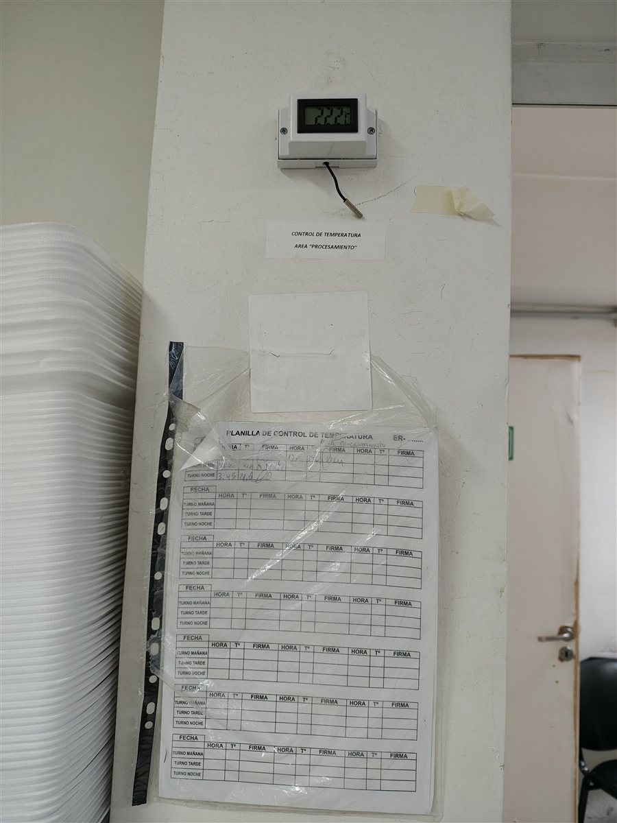 Planilla de control de temperatura en papel y termómetro analógico de pared, método de registro manual real en un área de procesamiento